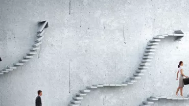 People walking on different staircases against a concrete wall.