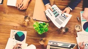 People working together at a table with charts and a laptop.