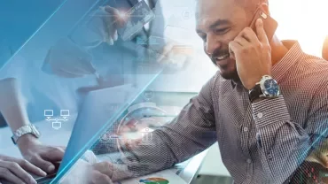 Person on phone working at a laptop with digital graphics overlay.