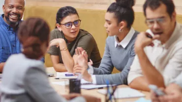 Group of men and women gathered at a table talking 