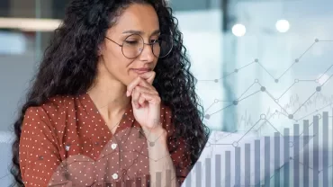Person working on a laptop with charts overlayed in the foreground.