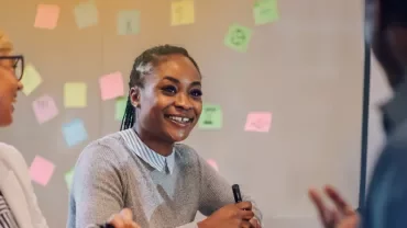 professionals talking with sticky notes in the background on a whiteboard