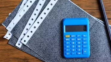 a calculator and pen on top of payslips