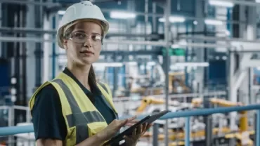 woman in hard hat holding clipboard in factory