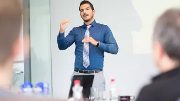 A young man in a suit half way through an interview presentation