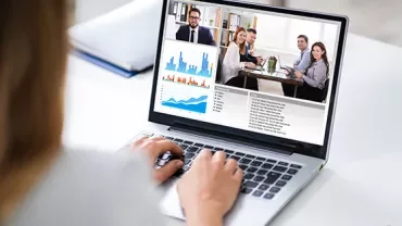 Person in a video conference with charts displayed on a laptop screen.