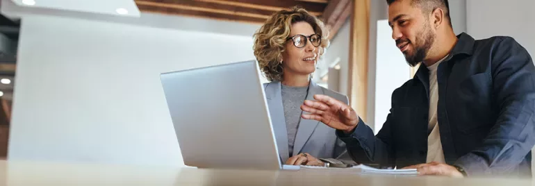 Two people in a discussion at a table with a laptop.