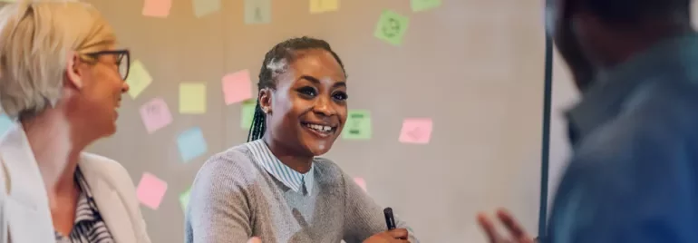 professionals talking with sticky notes in the background on a whiteboard